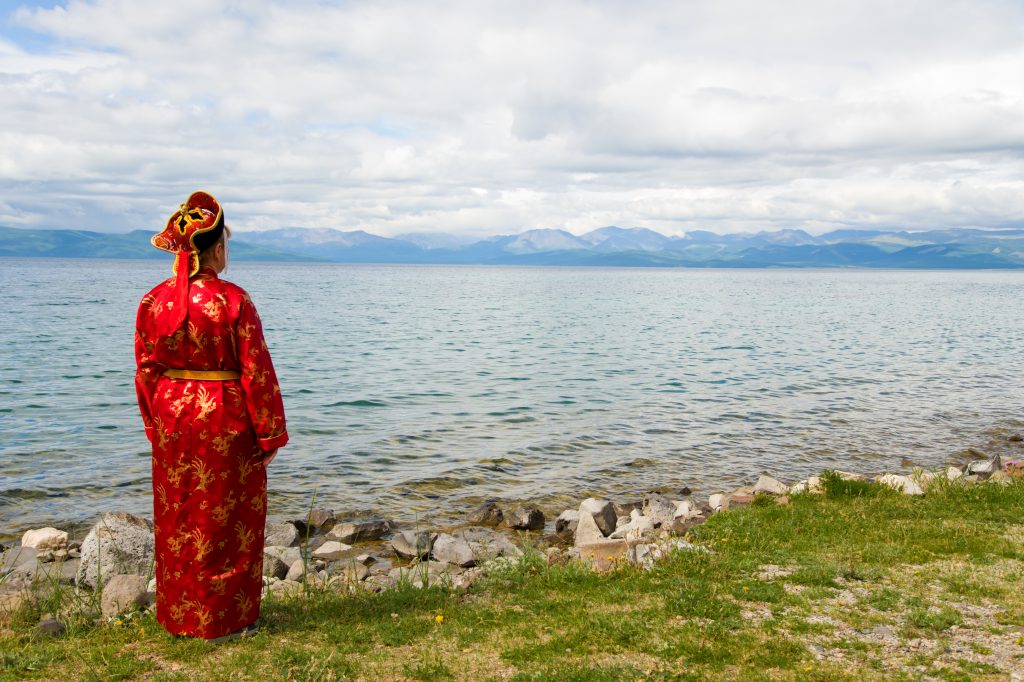 Women in traditional clothes looking at lake. Hovsgol, Mongolia